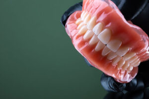 a full set of dentures with a doctor holding them up with a glove