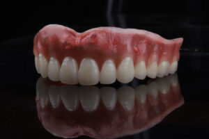 a top piece of dentures being shown with a black glossy floor
